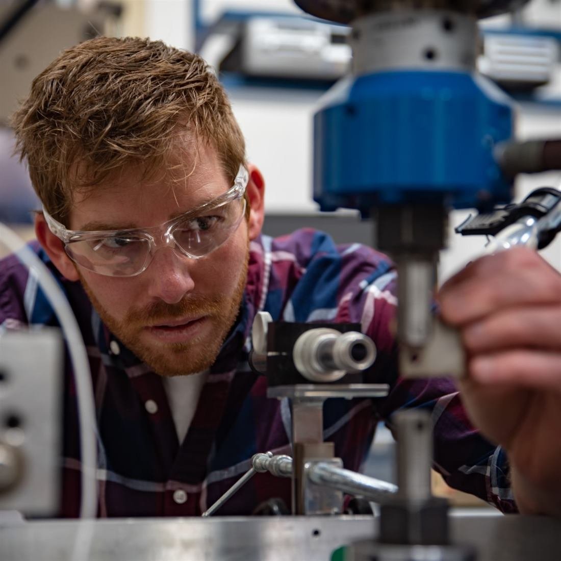Engineer testing a 3D-printed titanium part in a mechanical testing setup